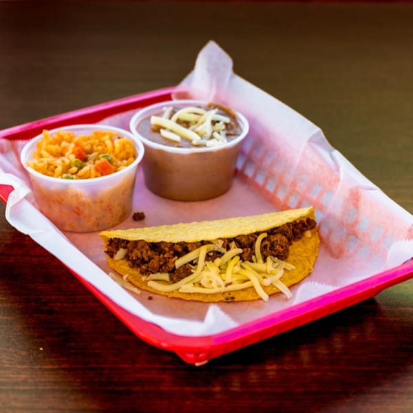 Uno Dos Tacos' beef taco with shredded cheese, rice, and beans in a red basket.
